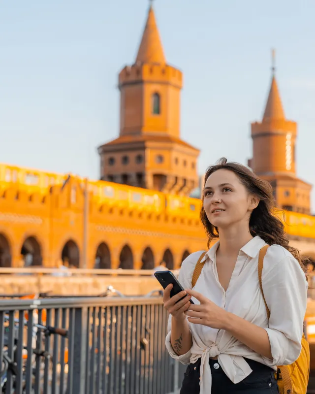 Frau mit Smartphone vor Oberbaumbrücke